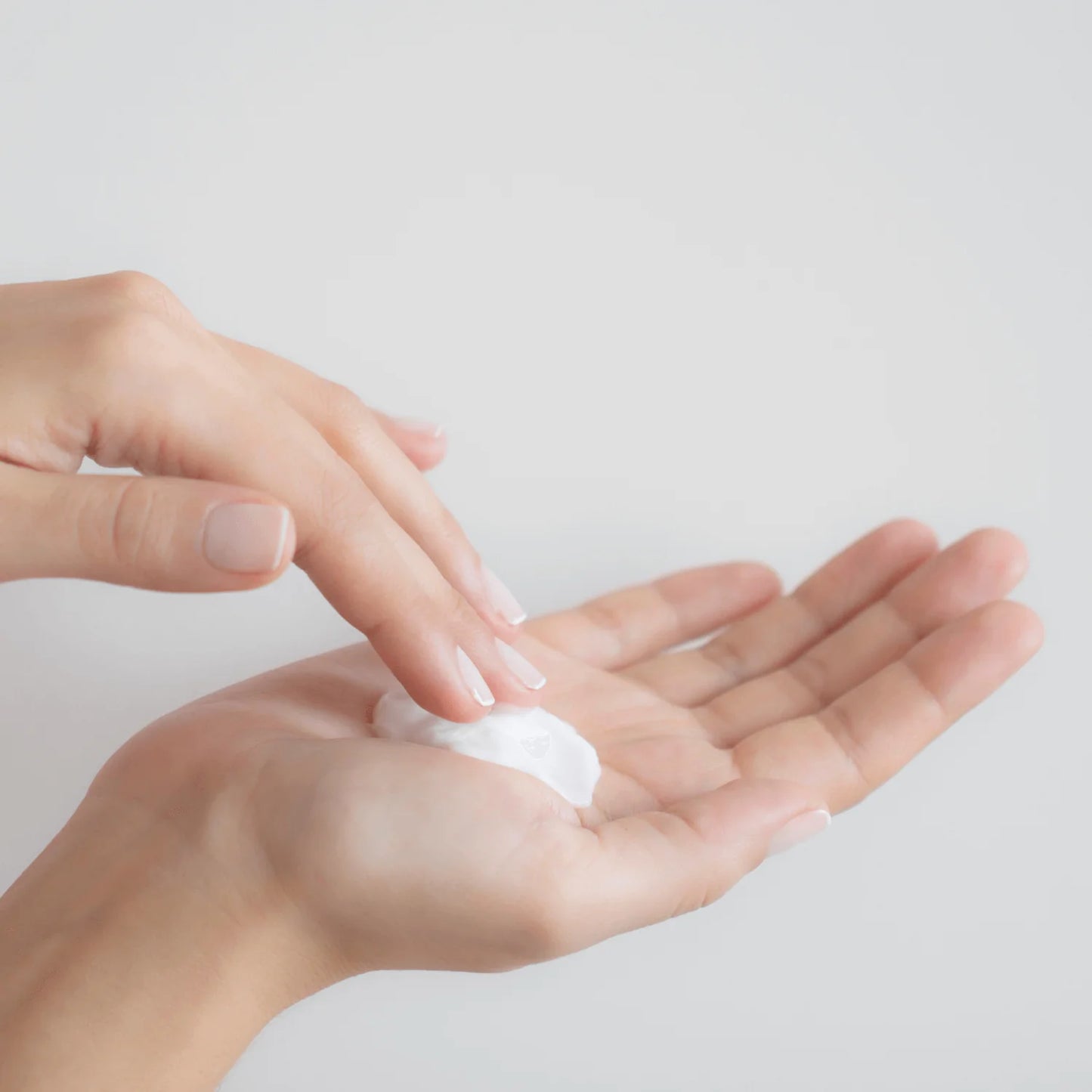 Close-up of Revision Skincare Gentle Facial Cleansing Lotion texture showing creamy hydrating cleanser on a hand for sensitive skin.