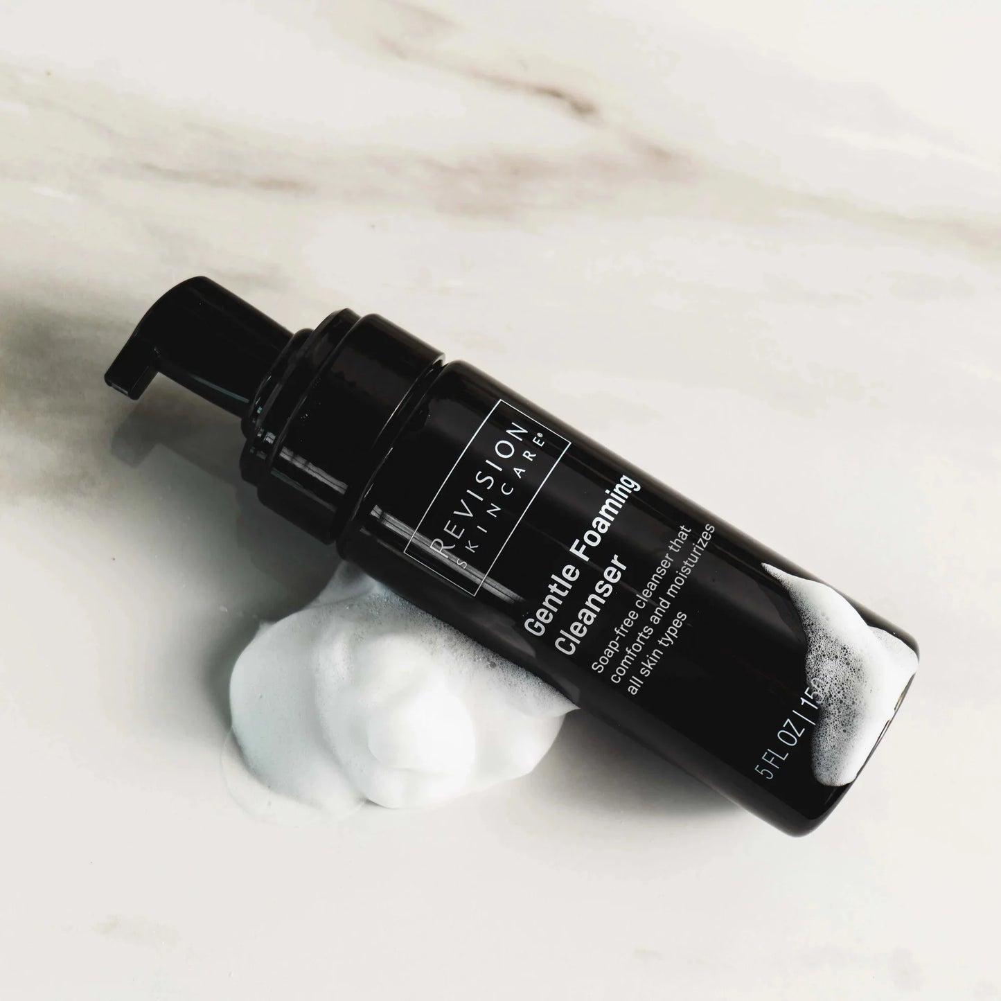 Revision Skincare Gentle Foaming Cleanser bottle with foam on marble background showing gentle hydrating cleanser for daily use.